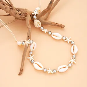 Gros plan d'un collier de coquillages bohème avec étoiles de mer sur une branche