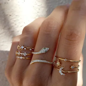 Detail of 7-piece gold ring set featuring snake motif and moon elements with green gemstones