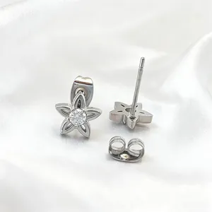 Silver star-shaped titanium steel studs with zircon stones on white silk background