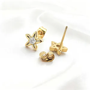 Elegant gold star stud earrings with central zircon inlay on white satin background