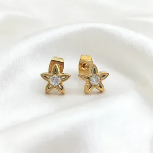 Detailed close-up of golden petal earrings with zircon inlay on a white silk background
