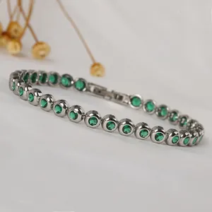 Close-up of sparkling green round zircons set in a polished silver-tone tennis bracelet