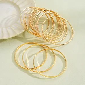 Dettaglio di bracciali bohémien dorati impilati su piatto di ceramica con incisioni fini