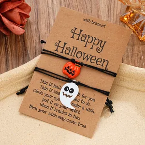 Detail von Halloween-Wunscharmbändern mit Kürbis- und Geist-Anhängern auf Kraftpapier