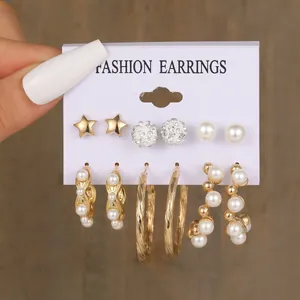 Dettaglio di un set da 6 paia di orecchini dorati con perle e strass su scheda espositiva