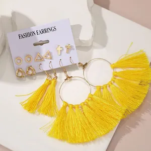 Set di orecchini bohémien dorati con nappe gialle, perle e perni geometrici su un cartoncino