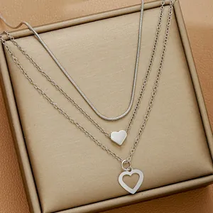 Détail d'un collier argenté à trois couches avec pendentifs cœurs pleins et évidés