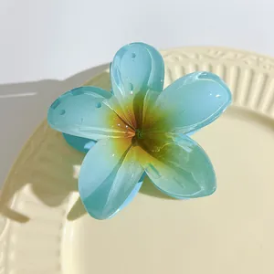 Detailed macro view of a 7cm light blue translucent frangipani flower hair claw clip