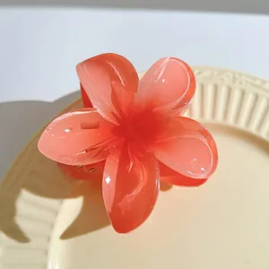 Detailed macro view of an orange translucent plumeria hair claw clip on a beige ceramic plate