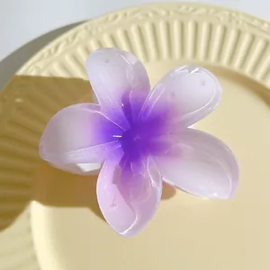 Detailed view of a 7cm purple plumeria hair claw clip on a textured ceramic plate