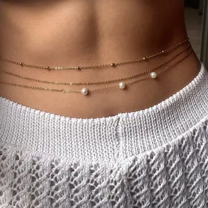 Three-layer gold waist chain with pearls and sequins worn over a white summer knit dress