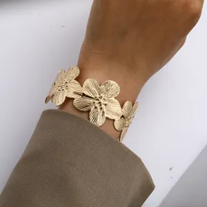Elegantes goldenes Blumenarmband mit strukturierten Blüten am Handgelenk über Anzug
