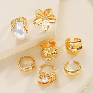 Set di 7 anelli dorati impilabili con perla barocca, fiore e metallo con texture unica