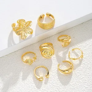 Set di 8 anelli dorati stile oceano con stelle marine conchiglie e fiori su sfondo bianco