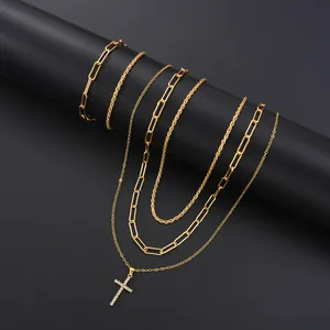 Primer plano de collares dorados de varias capas con un colgante de cruz de strass brillante