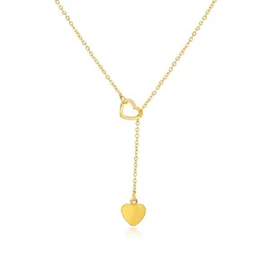 Macro detail of gold Y-shaped necklace featuring a hollow sliding heart and solid pendant