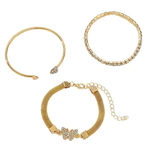 Conjunto de tres pulseras doradas con diamantes de imitación y lazo en fondo blanco