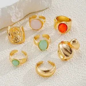 Detalle de anillos bañados en oro con textura irregular y gemas de resina de colores