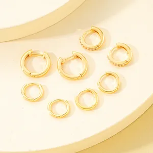 Detalle de cuatro pendientes de aro dorados con circonitas en soportes de exhibición