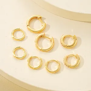 Detalle macro de set de pendientes de aro dorados con acabado pulido y circón púrpura