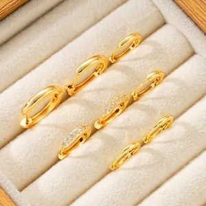 Detalle de aros bañados en oro con diseños minimalistas y adornos de cristales finos