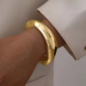 Minimalist chunky golden metal bangle with a high-gloss polished finish for women