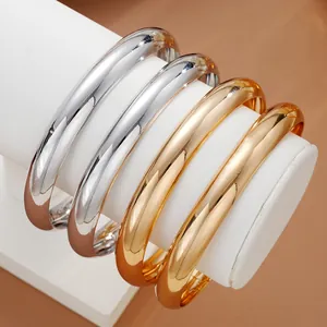 Set of four minimalist gold and silver polished metal bangles on a white display stand