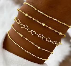 5-piece golden bracelet set featuring heart links and beaded chains on model wrist