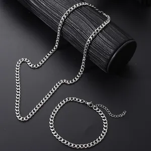 Detail of silver Cuban link chain necklace and bracelet set on black textured display