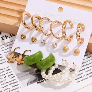 Close-up of 9-pair earring set with gold hoops, pearls, and resin on a display card