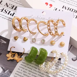 Detail view of gold hoop earrings set with pearls and green resin on jewelry card