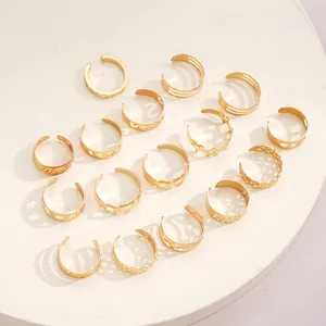 Close-up of 16-piece gold toe ring set with hollow heart and star patterns on white stand
