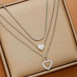 Détail d'un ensemble de trois colliers argentés avec pendentifs cœurs sur plateau à bijoux