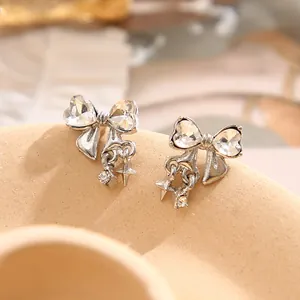 Detailed macro shot of silver bow stud earrings with heart crystals and star pendants