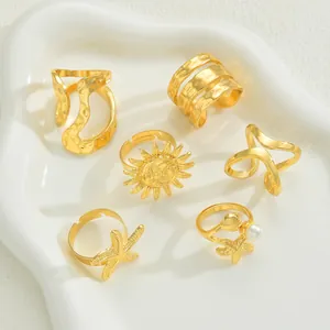 Detail von 6-teiligem Goldring-Set mit Seestern-Motiven und Perlen auf weißem Teller