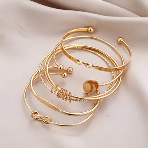 Detailed view of 5-piece gold geometric knot bracelet set on beige silk fabric