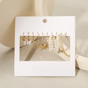 Détails de boucles d'oreilles créoles dorées et perles sur une carte d'exposition