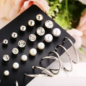 Detalle macro de set de 20 pares de pendientes con perlas y circonitas en tarjeta negra