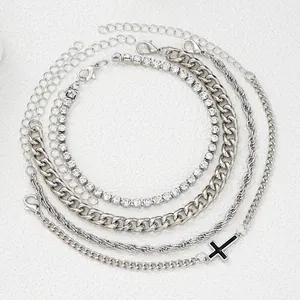 Dettaglio di cinque braccialetti d'argento con ciondolo a croce, catena cubana e strass