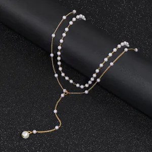 Close-up of golden double-layer Y-shaped necklace with elegant white pearls on black