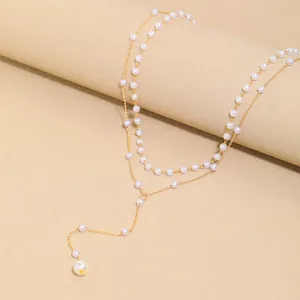 Close-up of golden double-layer necklace with white faux pearls and Y-shaped tassel drop