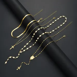 Détail d'un ensemble de colliers dorés avec pendentif croix et perles sur support noir