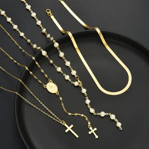 Détail d'un ensemble de quatre colliers dorés avec perles, pendentifs croix et chaîne serpent