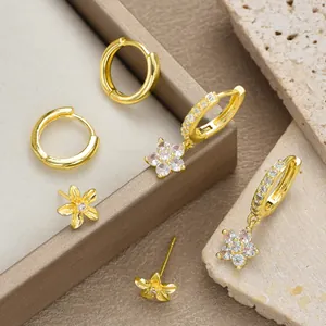 Λήψη macro από επιχρυσωμένους κρίκους και σκουλαρίκια λουλούδια με λαμπερά ζιργκόν