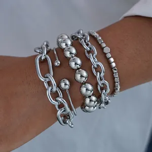 Close-up of stacked silver punk style bracelets with paperclip and bead chains on wrist