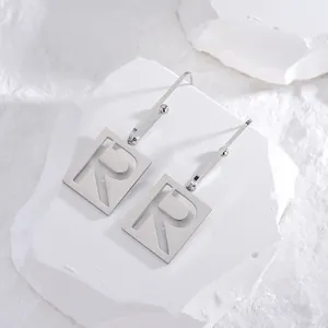 Minimalistische silberne Titanstahl-Ohrringe mit einem ausgestanzten Buchstaben R Anhänger