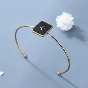 Bracciale rigido dorato minimalista con motivo quadrato nero e stella al centro