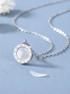 Détail du collier en titane argenté avec pendentif chiffres romains et nacre blanche