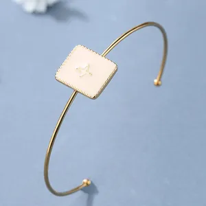 Bracciale rigido dorato minimalista con charm quadrato crema e motivo a stella