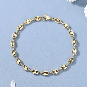 Poliertes goldenes Kaffeebohnen-Armband mit Karabinerverschluss auf blauem Hintergrund